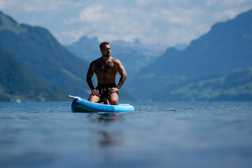Sexy man with paddle board. Man paddling on paddleboard. Muscular strong Hispanic man on sup board...
