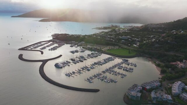 Port Airlie Beach Bay Lagoon Coral Sea marina jetty yachts sailboats aerial drone cloud layer mist sunrise morning rain clouds  heart of Great Barrier Reef Whitsundays Whitehaven forward pan up reveal