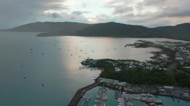Port Airlie Beach Bay Lagoon Coral Sea marina aerial drone mist sunrise morning rain clouds  heart of Great Barrier Reef Whitsundays Whitehaven jetty yachts sailboats  circle right motion
