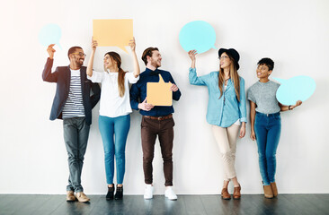 Team, happy and speech bubble at wall for opinion, review or comment on social media. Diverse group, text box or sign for voice, idea or vote in studio with smile, casual fashion and white background