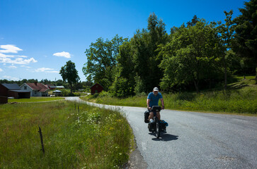 Bicycle tourism in Sweden, Man is cycling on rural road in Scandinavia summer sunny day, Long distance cyclist solo travel around the world