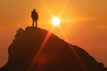 Naklejka premium Silhouette of a man standing on the top of a mountain in the ray