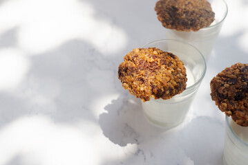 banana chocolate oatmeal cookies with milk on marble table in morning sunlight.