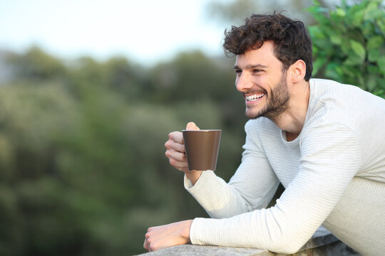 Happy man in a terrace drinking coffee looking away - Powered by Adobe