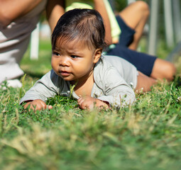 6 month old Latin baby lying face down on the grass in an outdoor park
