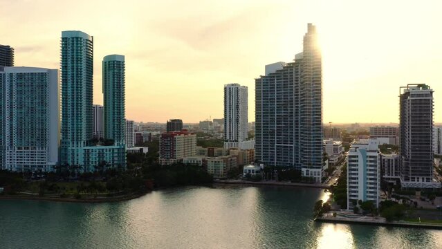 Captivating aerial view of Miami skyline and waterfront during a stunning golden sunset, with buildings reflecting in the calm bay, creating a mesmerizing scene of beauty and tranquility. 4k footage