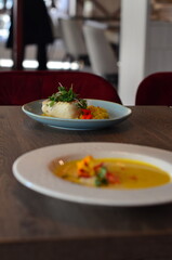 yellow vegetable soup with herbs, squid, pumpkin soup, herbs, plate, serving restaurant table, lunch menu 