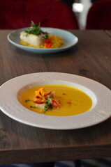 yellow vegetable soup with herbs, squid, pumpkin soup, herbs, plate, serving restaurant table, lunch menu 