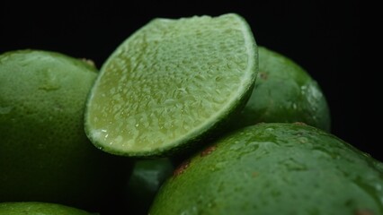 Slices of lime are meticulously arranged in a pile, set against a black background. Each lime slice...