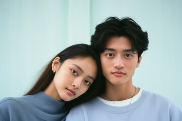 Photo of a young couple, age 19, Asian, sitting closely, first love, pastel blue background