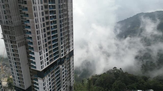 Drone flies in the vicinity of skyscrapers under construction in the genting highlands in malaysia - background nature and many mountains
