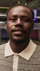 Vertical tilt up portrait of joyful African American guy in bowling shoes and casualwear posing for camera with ball, standing on alley with lanes in background - Powered by Adobe