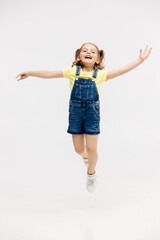 Little girl dancing in the studio on a white background. Happy energetic girl having fun and enjoying her childhood. Concept of fashion, style and happy children's emotions.