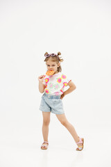 Happy little cute girl with a lollipop on a white background. Happy child enjoying childhood.