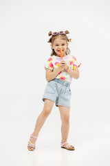 Happy little cute girl with a lollipop on a white background. Happy child enjoying childhood.