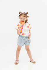 Happy little cute girl with a lollipop on a white background. Happy child enjoying childhood.