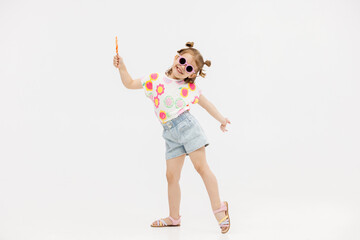 Happy little cute girl with a lollipop on a white background. Happy child enjoying childhood.