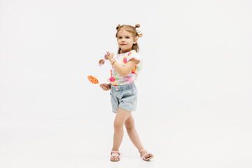 Happy little cute girl with a lollipop on a white background. Happy child enjoying childhood.