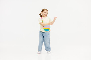 Fashionable, stylish little girl dancing, having fun and posing on a white studio background. Fashion, children's clothing and entertainment concept.