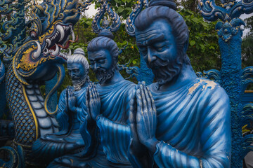 Statues of men praying at the blue temple in Chiang Rai, Thailand.
