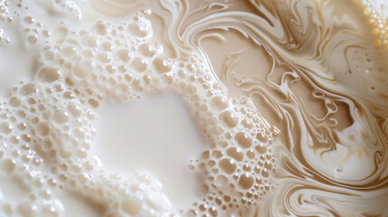 Obraz premium Large drops of milk mixed with coffee forming an abstract pattern. Milk and coffee flow smoothly into each other, creating a marble effect with bubbles on the surface