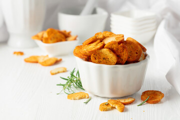 Spicy bruschetta crackers with rosemary on a white kitchen table.