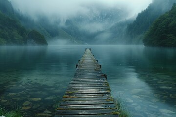 A serene foggy lake with a wooden dock stretching into the tranquil water, surrounded by mist-covered mountains, creating a peaceful and contemplative scene.