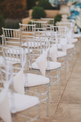 Decorated ceremonial area outdoors with modern transparent chairs.  wedding ceremony details. chairs for guests at a luxury wedding ceremony