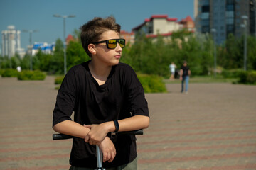 Teen boy riding on rented electric scooter through the streets of the city at summer. School boy...