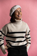 Studio shot of amazing french girl in beret and eyeglasses smiling isolated on pink background