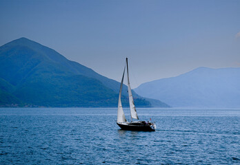 Fototapeta premium Sailing boat on a Lake Maggiore with Mountain in a Sunny Summer Day in Ascona, Ticino, Switzerland.