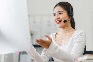 Smiling woman wearing headset, participating in video conference call from home office, using computer for virtual communication. Soft focus