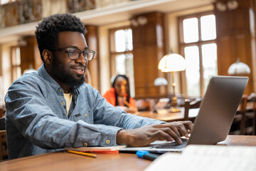 Dark-skinned young man working online in the library