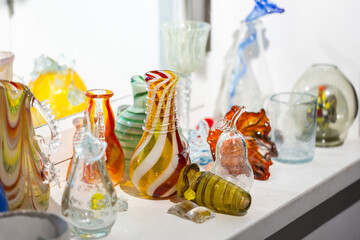 Colorful craft glasses and vases are on a windowsill, close-up