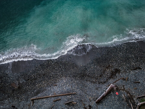 Aerial view of serene rocky beach with pebbles and driftwood, Sooke, British Columbia, Canada.