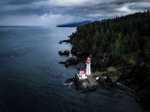 Aerial view of rocky shore with lighthouse overlooking ocean and forest, Sooke, British Columbia, Canada.