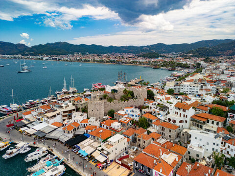 Aerial view of vibrant old town with castle, boats, and mountains, Marmaris, Turkey.