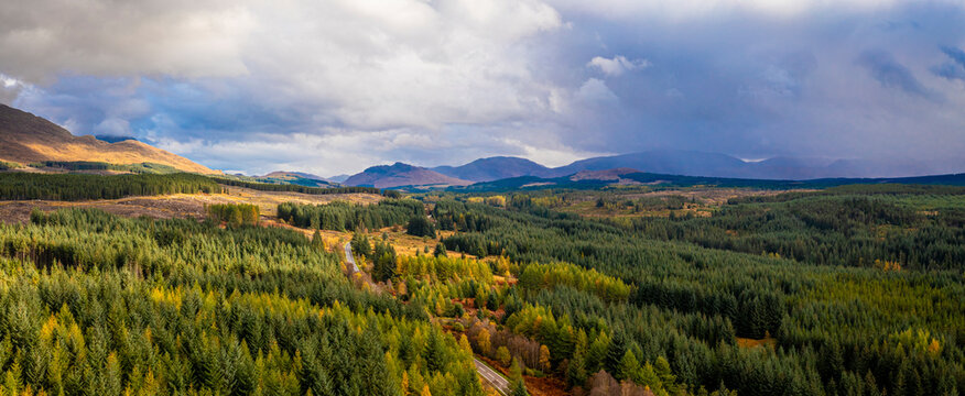 Aerial view of lush forest and majestic mountains in Roy Bridge, Scotland.