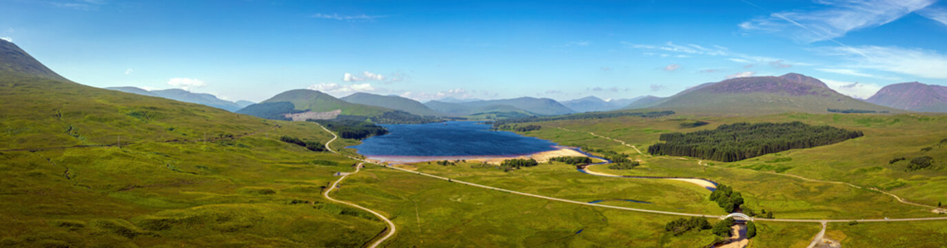 Aerial view of Loch Tulla with serene lake, green hills, and majestic mountains, Bridge of Orchy, Scotland, United Kingdom.