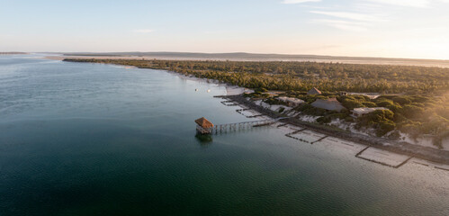 Aerial view of Thatched Pier, ocean, coastline, forest, houses, Ilha Lunene, Inhambane Province, Mozambique.
