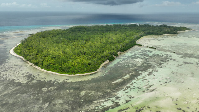 Aerial view of secluded tropical island with lush forest and serene lagoon, Poivre Island, Seychelles.