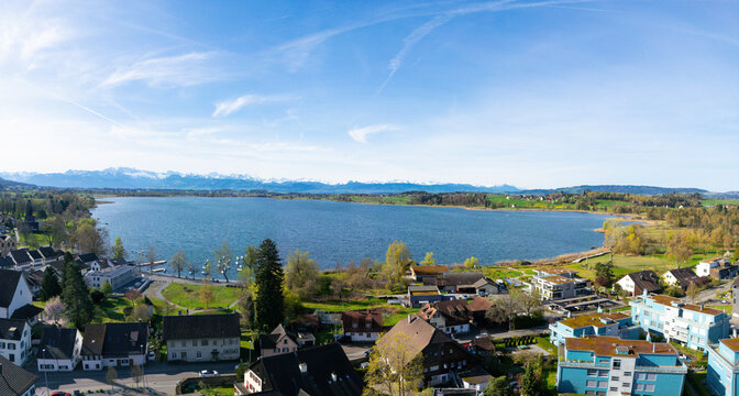 Aerial view of serene village with lake, mountains, and rooftops, Pfaffikon ZH, Switzerland.