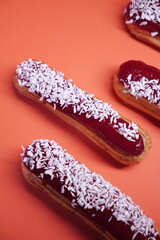 beautiful delicious eclair with coconut cream filling and raspberry jelly. confectionery, sweets. close up. coconut flakes. modern popular dessert. european pastry