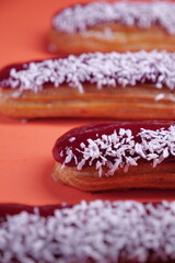 beautiful delicious eclair with coconut cream filling and raspberry jelly.  confectionery, sweets. close up. coconut flakes. modern popular dessert. european pastry