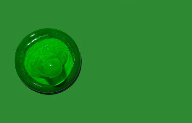 Green condom on a green background. Top view. Space for text.