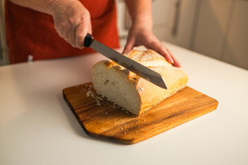 Whole grain bread put on kitchen wood plate with a chef holding gold knife for cut. Fresh bread on table close-up. Fresh bread on the kitchen table The healthy eating and traditional bakery concept