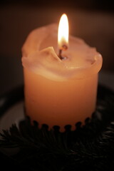 Christmas and New Year cozy  atmosphere. white candle in a black candlestick is burning against the background of blurry Christmas tree garlands. candle flame
