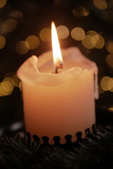 Christmas and New Year cozy  atmosphere. white candle in a black candlestick is burning against the background of blurry Christmas tree garlands. candle flame
