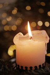 Christmas and New Year cozy  atmosphere. white candle in a black candlestick is burning against the background of blurry Christmas tree garlands. candle flame
