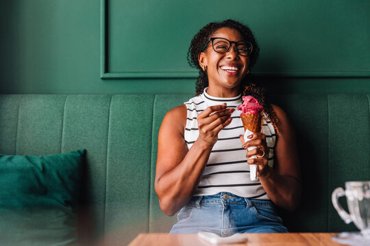Happy woman enjoying ice cream in a cozy cafe setting